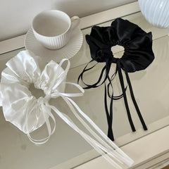 black and white satin scrunchies with long ribbon ties next to a teacup