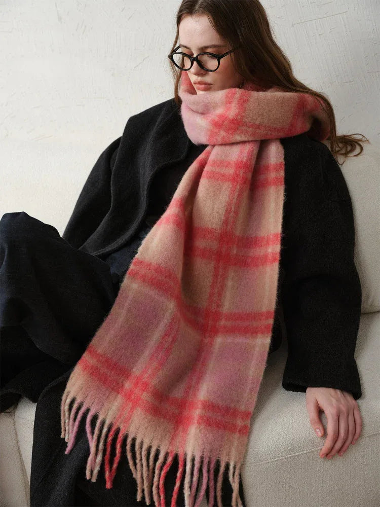 Woman sitting down wearing a black coat and a pink plaid scarf.