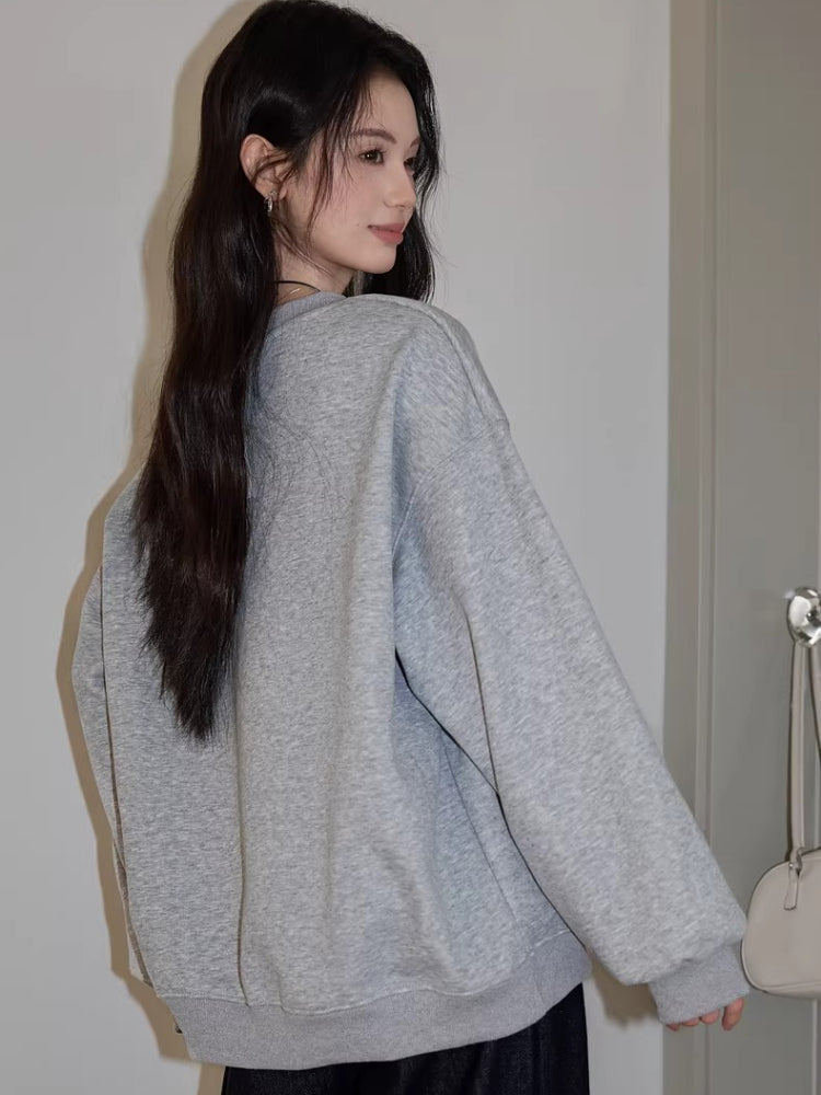 Back view of a woman wearing a grey crew neck sweatshirt