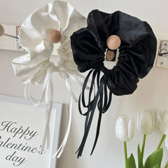 black and white satin scrunchies with long ribbon ties hanging on a wall