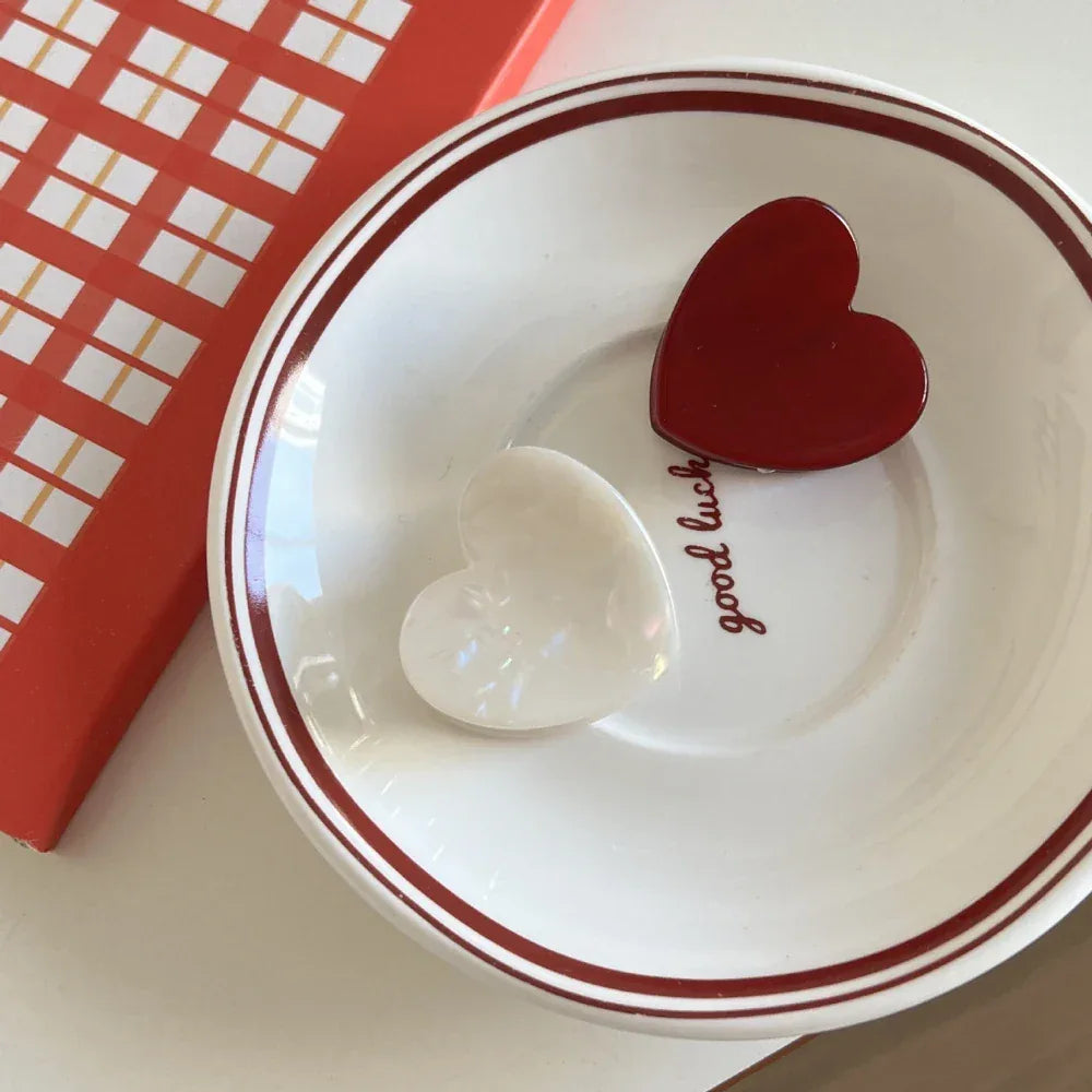 White and red heart-shaped hair clips on a saucer