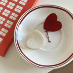 White and red heart-shaped hair clips on a saucer