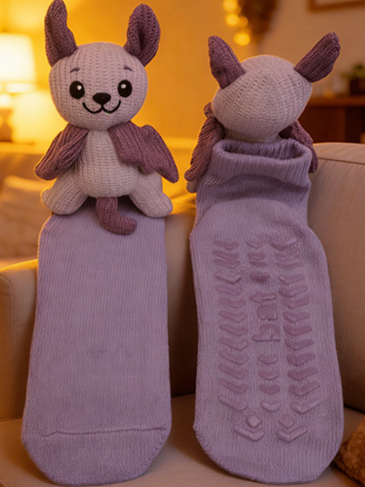 Two light purple ankle socks laid flat, one with the plush bat character attached and the other showing the gripper sole.