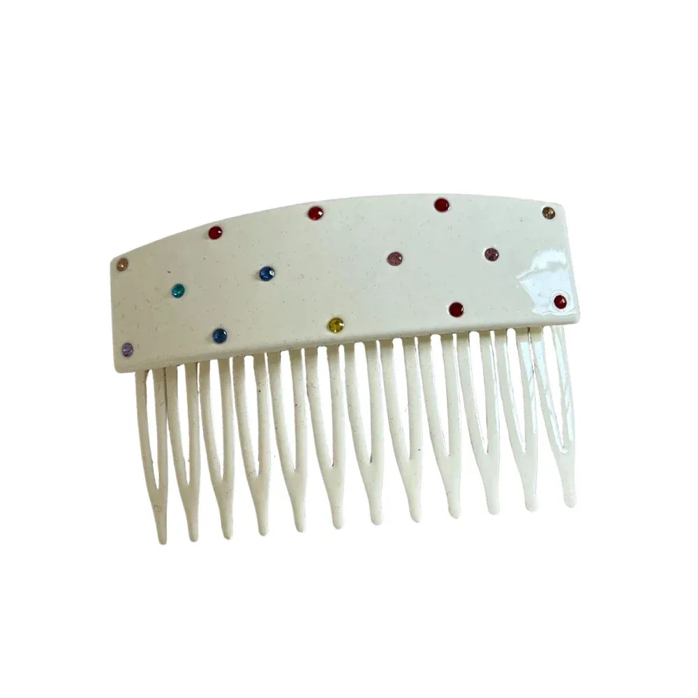 A white hair comb with colorful rhinestones scattered across the top.