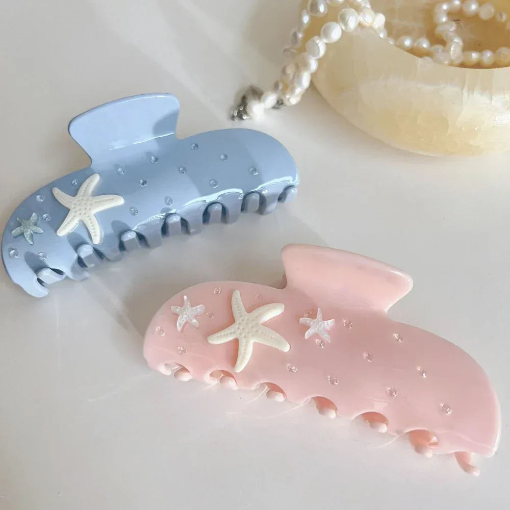 light blue and pink pastel claw clips with starfish and rhinestones, displayed with a pearl necklace