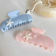 light blue and pink pastel claw clips with starfish and rhinestones, displayed with a pearl necklace