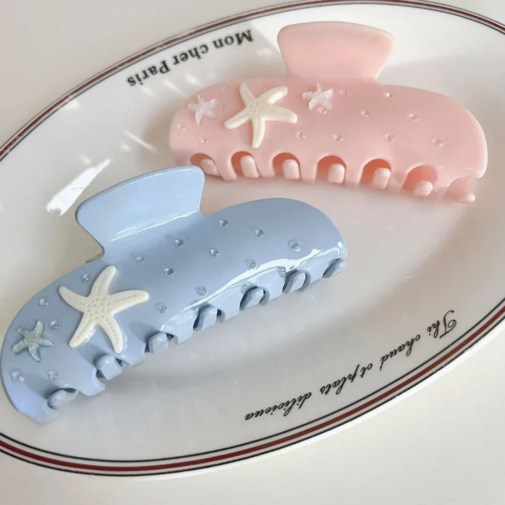 light blue and pink pastel claw clips with starfish and rhinestones, presented on a white oval dish