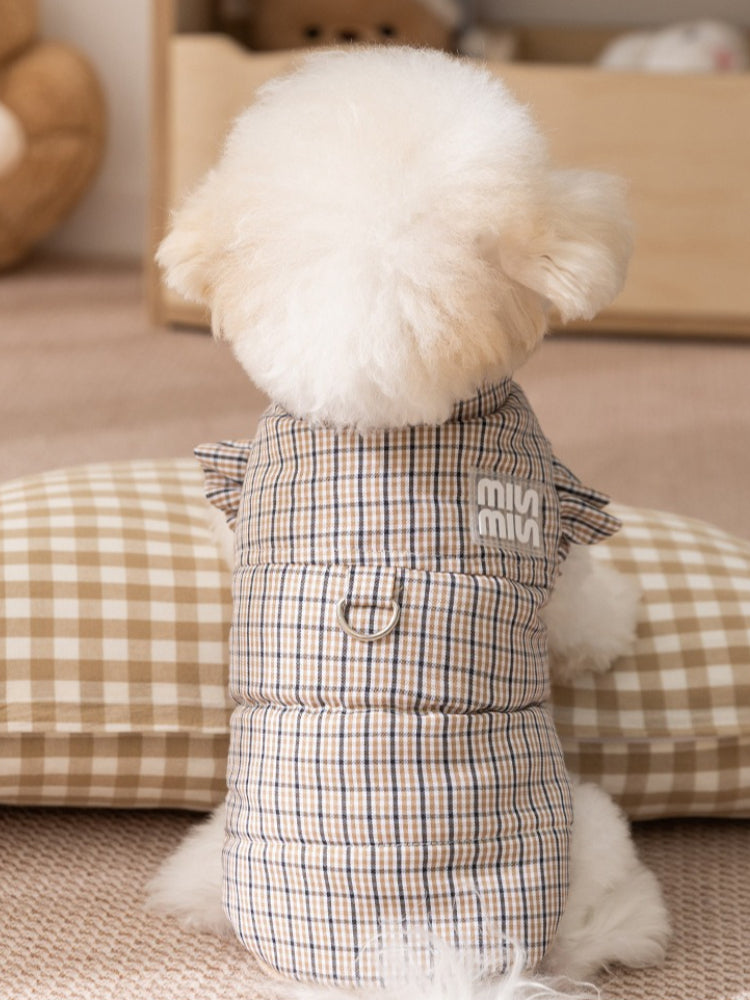 The back of a white dog wearing a brown plaid dog vest, showing the d-ring and logo detail.