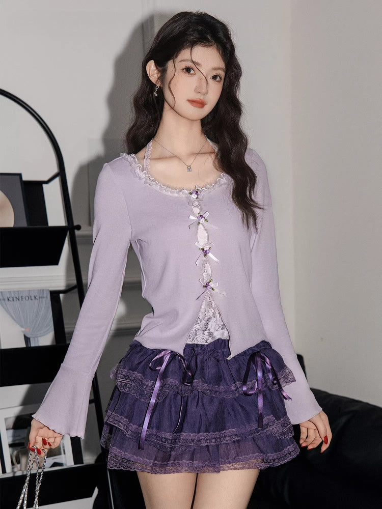 Close-up of a woman wearing a lavender ribbed knit cardigan with lace trim and bow details over a white camisole, paired with a purple tiered ruffled skirt.