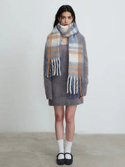 Full body shot of a woman in a grey knit dress and plaid scarf