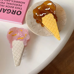 Two ice cream cone hair clips, one pink and one brown, next to a pink book