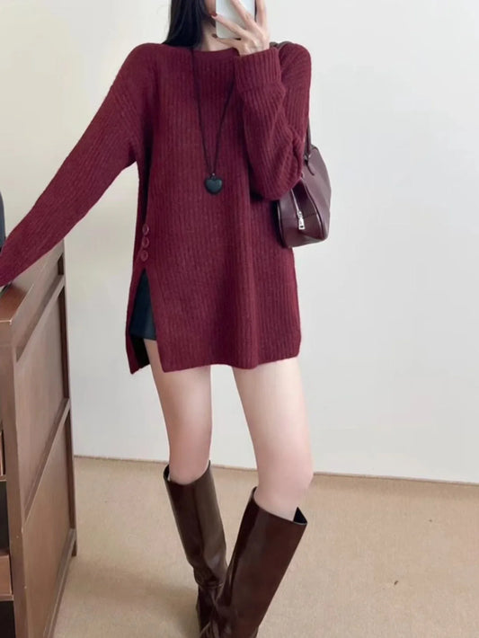 Full body shot of a woman in a burgundy ribbed knit longline tunic with side slits and buttons, black shorts, and brown boots.