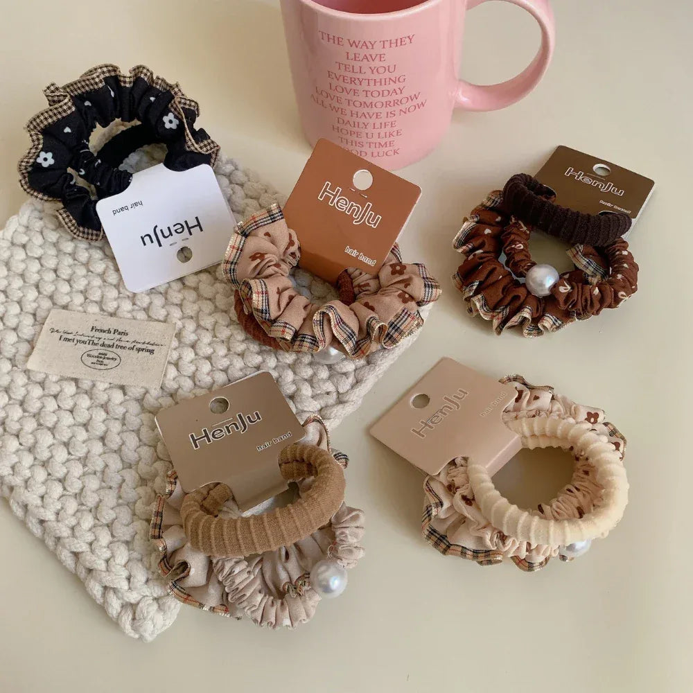 Assortment of scrunchies displayed with a pink mug and pearl necklace