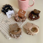 Assortment of scrunchies displayed with a pink mug and pearl necklace
