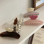 A collection of patterned hair claw clips on a white shelf