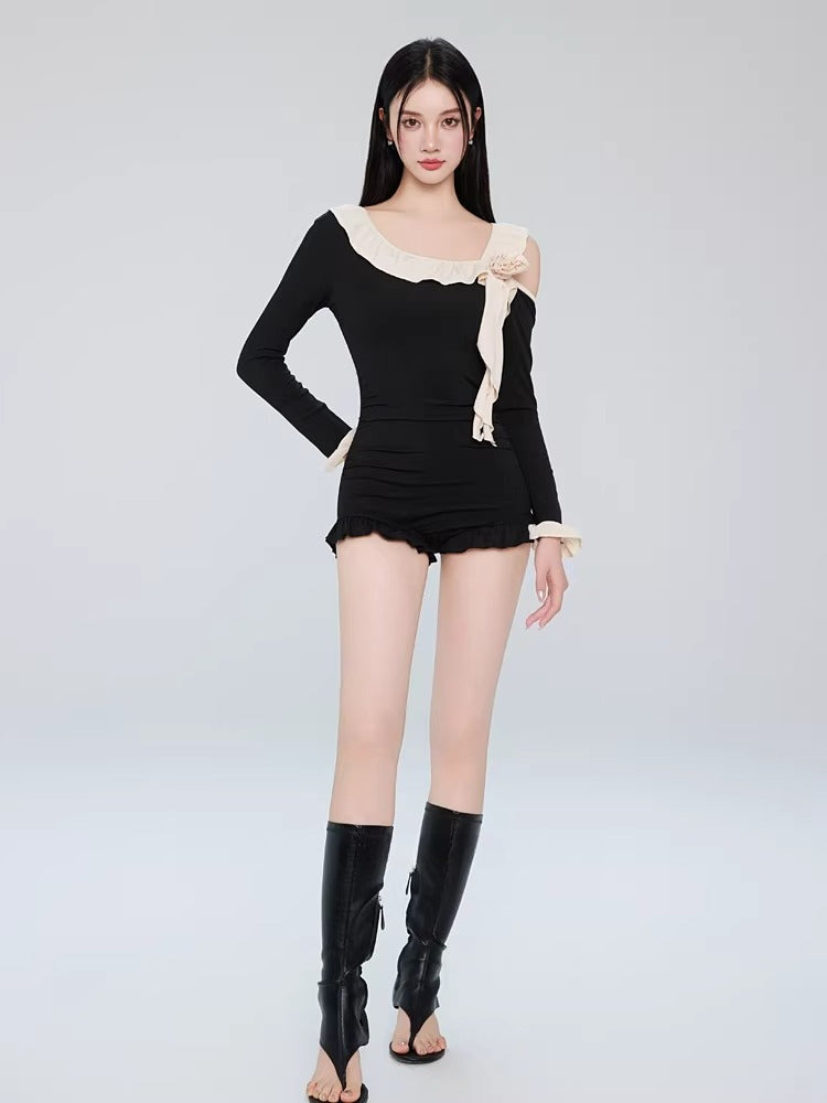 Full-length shot of a woman in a black one-piece swimsuit with ruffle trim and decorative floral accent, paired with tall boots.
