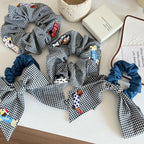 Collection of black and white gingham scrunchies with various embroidered dog appliques and denim accents