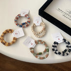 A collection of fuzzy striped hair ties in various color patterns, displayed on a white surface.