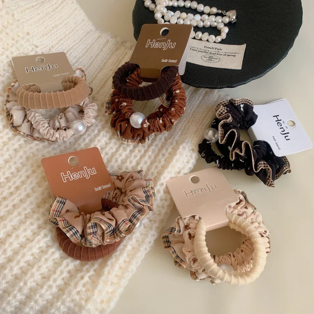 Several scrunchies arranged on a white textured surface, with a black decorative item in the background