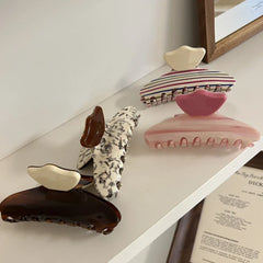 A collection of patterned hair claw clips on a white shelf