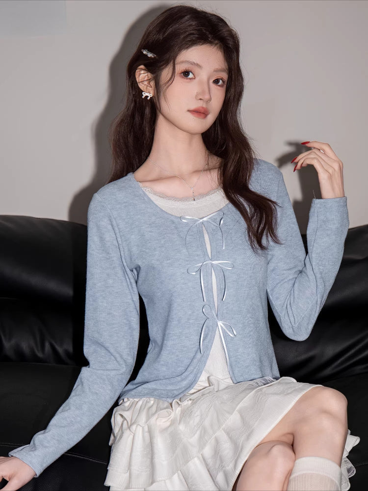 Close-up of a woman in a light blue cardigan and white skirt, showing off her outfit details.