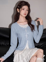 Close-up of a woman in a light blue cardigan and white skirt, showing off her outfit details.