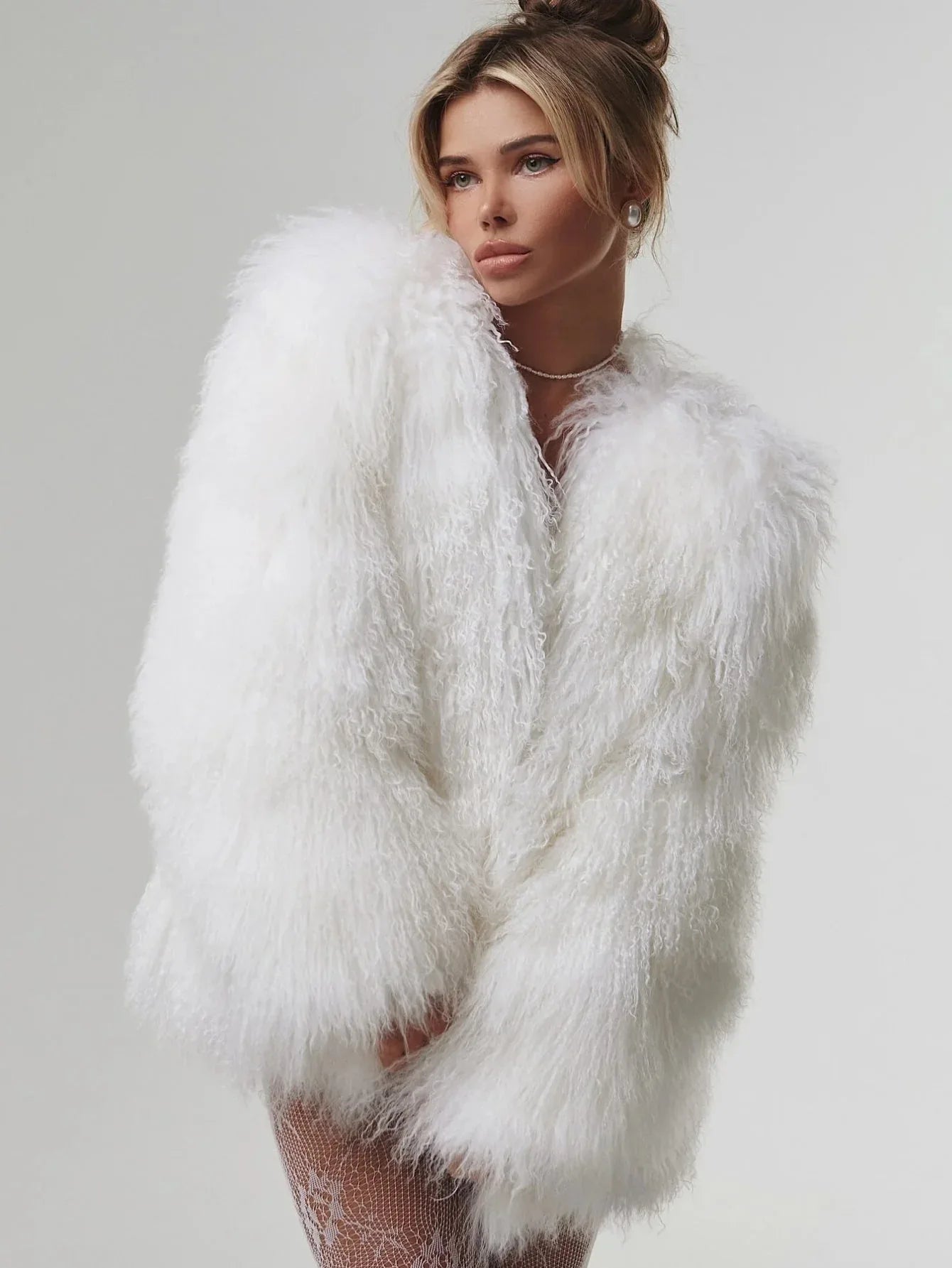 Woman wearing a white fluffy faux fur oversized jacket and white lace stockings Main image