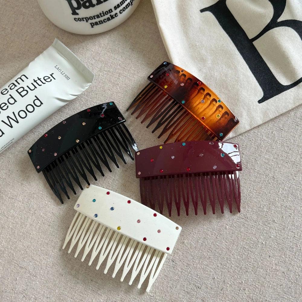 A close-up view of four embellished hair combs in black, tortoiseshell, burgundy, and white, set against a neutral background.