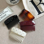 A close-up view of four embellished hair combs in black, tortoiseshell, burgundy, and white, set against a neutral background.