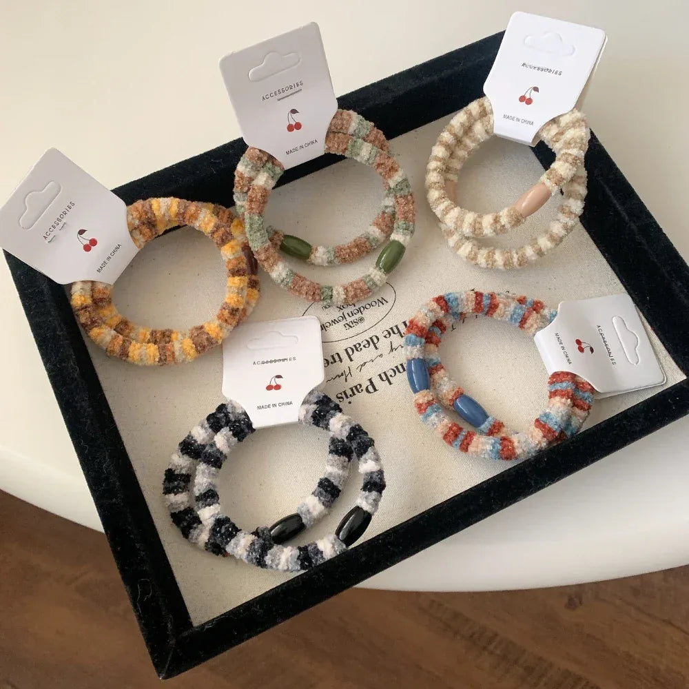 A selection of fuzzy hair ties in a tray, showcasing diverse color combinations and bead details.