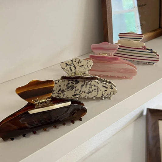 A collection of patterned hair claw clips on a white shelf