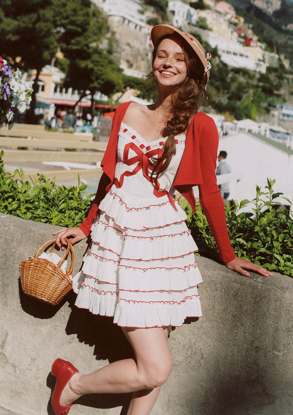Detail of the tiered ruffle skirt and bow detail on a white dress with red trim.