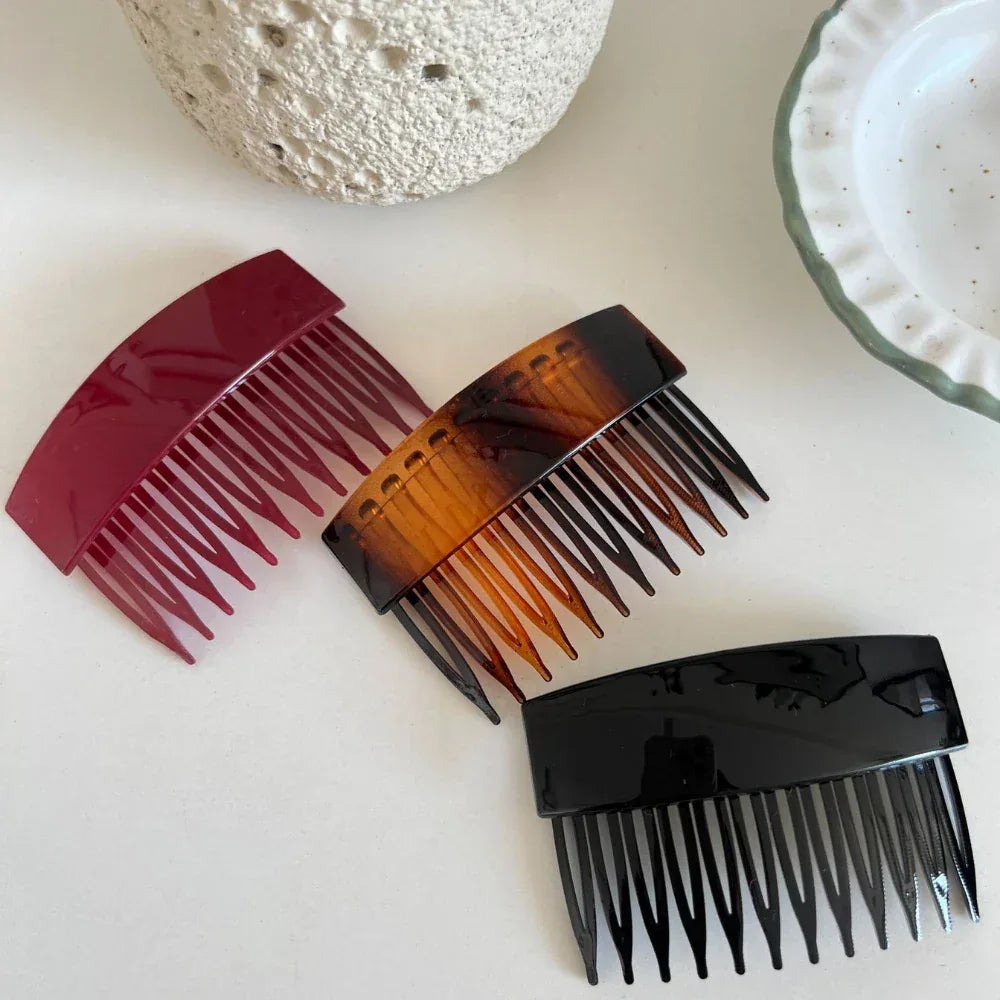 three hair combs in burgundy, tortoiseshell, and black laid out on a white surface