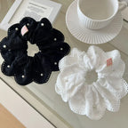 Black and white scrunchies with lace and pearl details on a glass surface