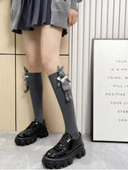 Person standing, showcasing grey knee-high socks with a bunny charm and black platform shoes.