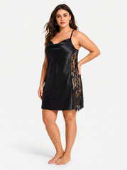 Plus size model wearing a black satin slip dress with lace side panels from a three-quarter front view, with her hand on her hip.