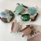 Various turtle hair clips, including large and small sizes, in pastel and jewel tones