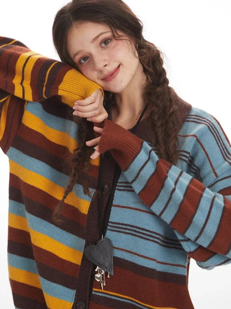 Close-up of a woman wearing a striped knit cardigan, leaning her head on her arm and smiling.