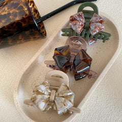 Bow claw clips displayed on a tray with a patterned cup