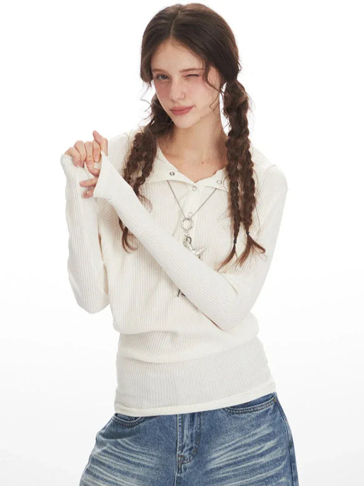 Woman posing in a white ribbed knit long-sleeve shirt and distressed wide-leg blue jeans.
