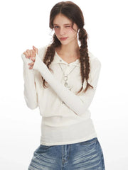Woman posing in a white ribbed knit long-sleeve shirt and distressed wide-leg blue jeans.