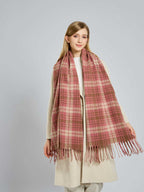 Front view of a woman modeling a large, fringed plaid scarf.