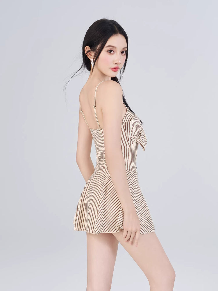 Woman shown from the side, wearing a striped one-piece outfit with a flared hem.
