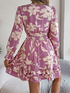 back view of a woman in a purple floral print mini dress with smocked waist and ruffled hem