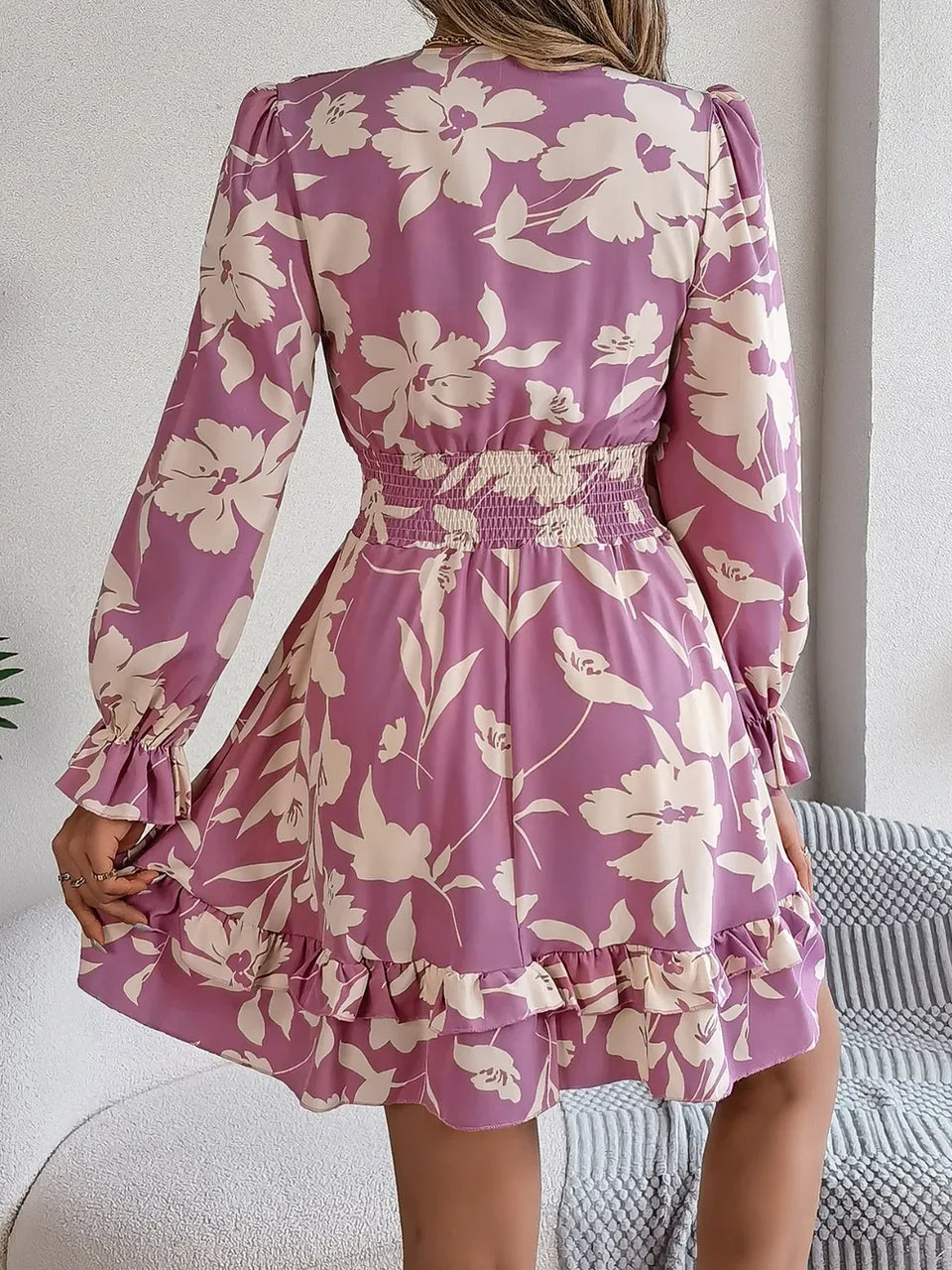 back view of a woman in a purple floral print mini dress with smocked waist and ruffled hem Secondary image
