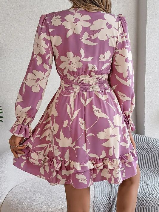 back view of a woman in a purple floral print mini dress with smocked waist and ruffled hem