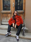 Woman wearing a red fur jacket and black pants sitting on steps