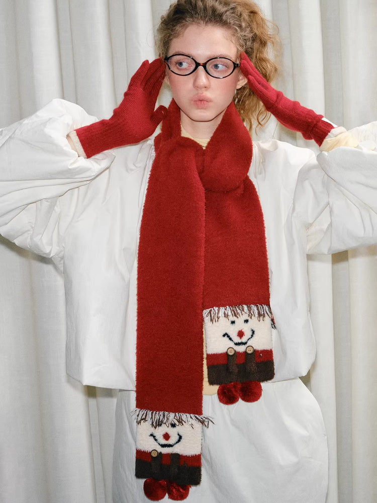 Young woman wearing a red scarf with a snowman design and red gloves.