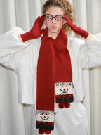 Young woman wearing a red scarf with a snowman design and red gloves.