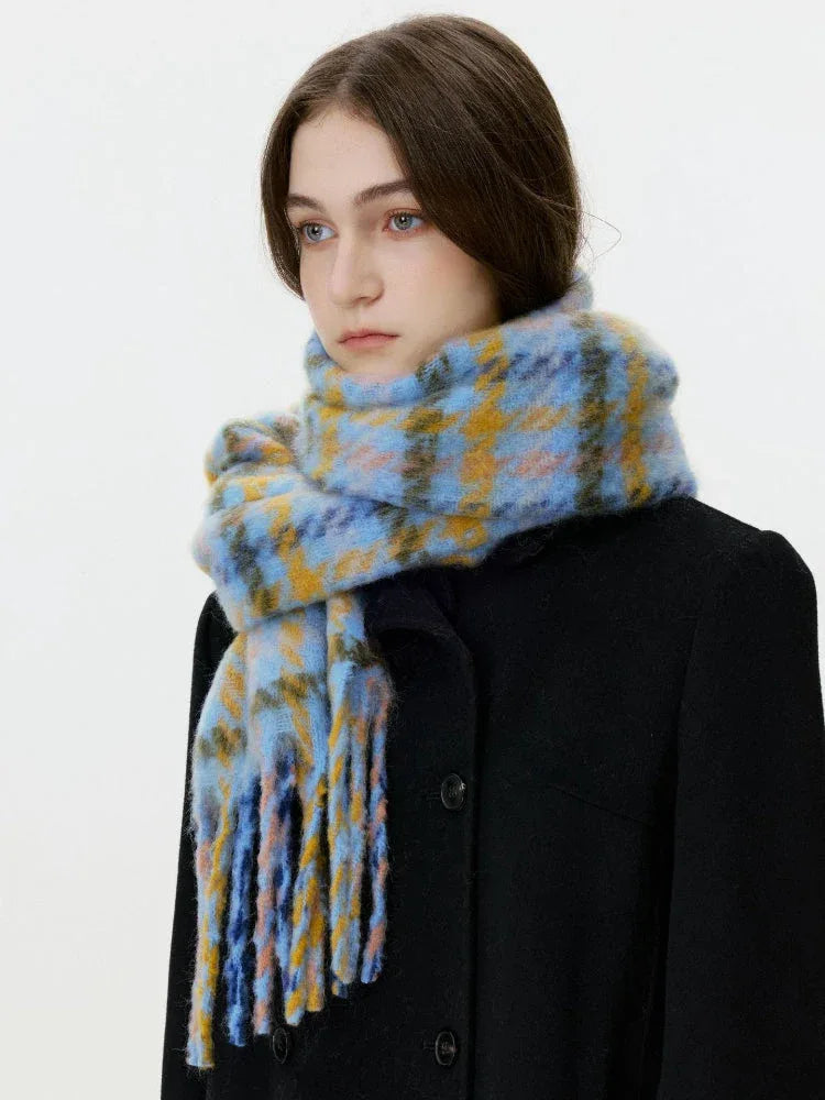 Close-up of a woman wearing a black coat and a blue and yellow plaid scarf with fringe